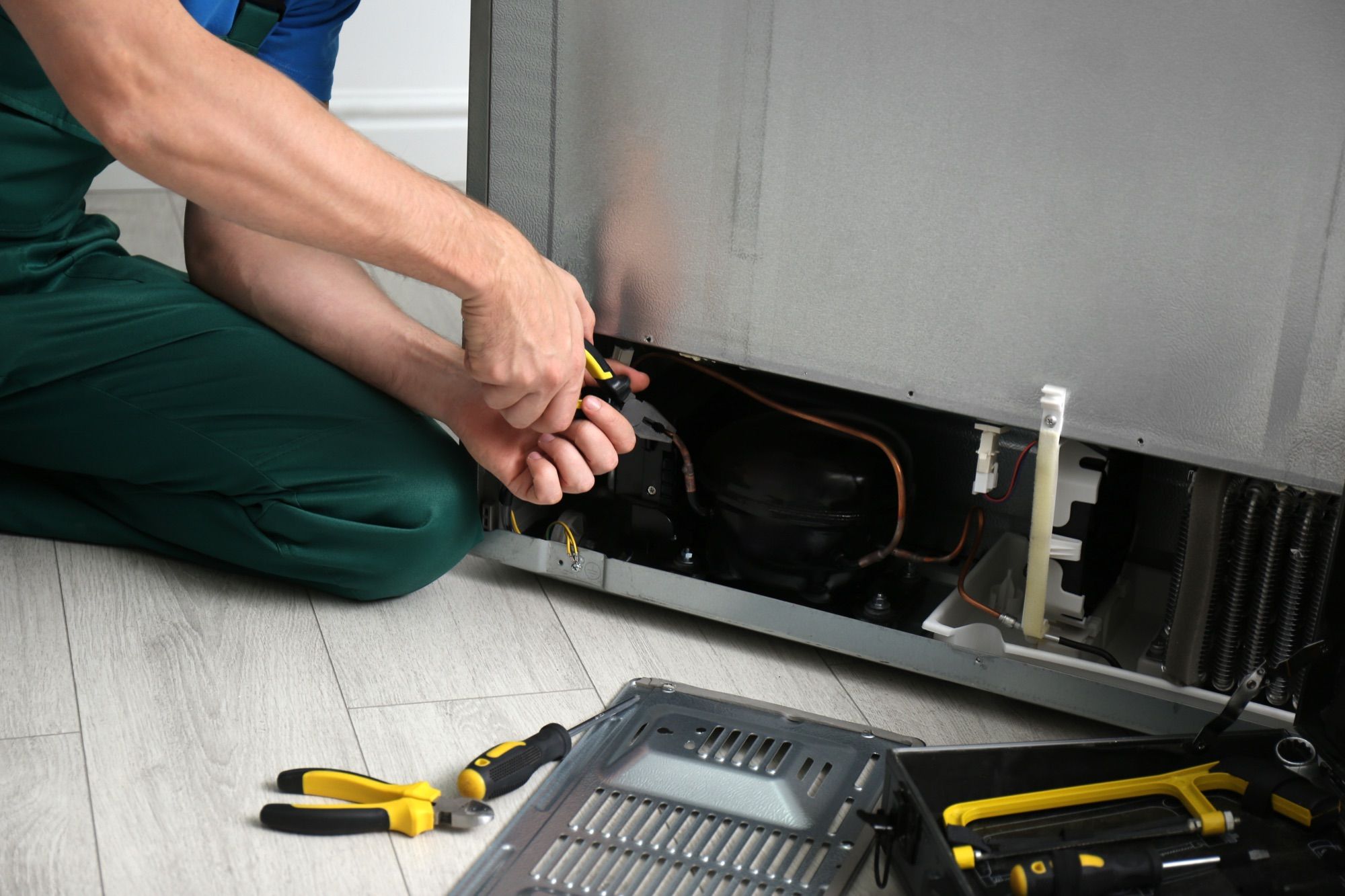 Técnico reparando un frigorífico en una cocina